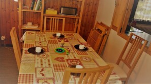 A dining area with a table set for four, surrounded by wooden chairs. A television is mounted on the wall above the table. - 2nd floor, view mountain, tv, 58m², Le Grand Bornand (Le Grand-Bornand)