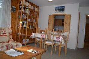 A cozy living room with a wooden bookshelf, a dining table with chairs, and a sofa. - Resort center, 2nd floor, view mountain, tv, 58m², Le Grand Bornand (Le Grand-Bornand)
