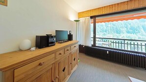 A room with a wooden dresser, a television, a speaker, and a radiator. - Resort center, 2nd floor, view mountain, tv, 58m², Le Grand Bornand (Le Grand-Bornand)