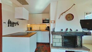A modern kitchen with a central island, a built-in microwave, and a stone fireplace.
