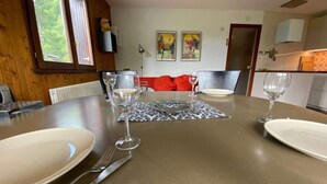 A dining table set with plates, cutlery, and wine glasses, with a red sofa and artwork in the background.