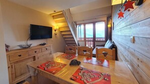 A dining area with a wooden table, chairs, and a television mounted on the wall. - 10m from ski slopes, 5th floor, view mountain, balcony, tv, ski locker, 65m², Montchavin La Plagne (Bellentre)