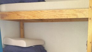 Una cama litera con tres niveles, cada uno con un colchón y almohadas.