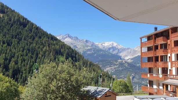 Vista de la montaña con un edificio de madera con balcones y cielo despejado.