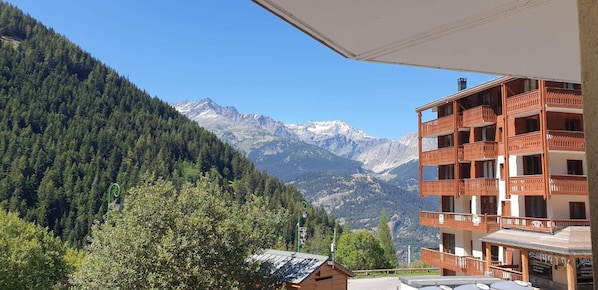 A mountain view with a wooden building featuring balconies and a clear sky.
