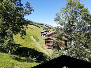 A chalet-style building with a balcony, surrounded by lush greenery and hills in the background. - 100m from ski slopes, 3rd floor, balcony, ski locker, 27m², Valmorel (Valmorel)