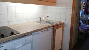A compact kitchen with a dishwasher, a sink, and wooden cabinets. - 3rd floor, balcony, ski locker, 27m², Valmorel (Valmorel)