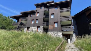 A modern multi-story building with balconies, stone base, and a clear sky. - 3rd floor, balcony, ski locker, 27m², Valmorel (Valmorel)