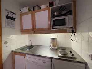A compact kitchen with a microwave, coffee maker, and a dishwasher.