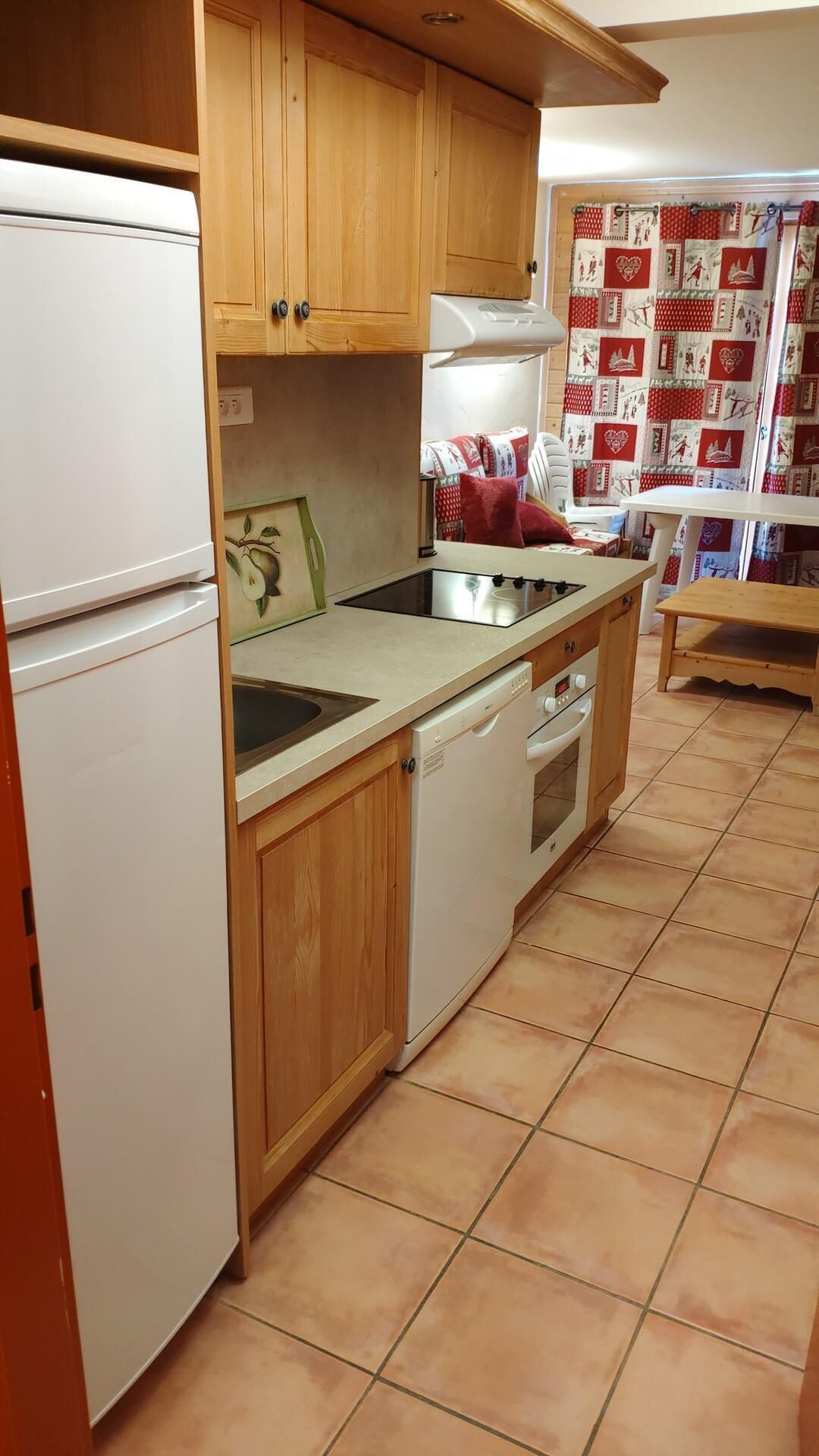 A compact kitchen with wooden cabinets, a white refrigerator, a dishwasher, and a stove.