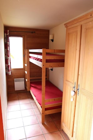 A small, wooden room with bunk beds, a wardrobe, and a heater. - 1st floor, balcony, ski locker, 40m², Pra Loup (Pra Loup)