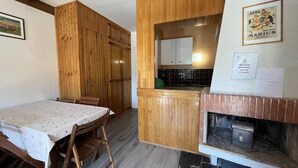 A compact kitchen with wooden cabinets, a dining table with chairs, and a built-in stove. - Ground floor, balcony, tv, 30m², Pra Loup (Pra Loup)