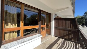 A building with large glass windows, a wooden deck, and a metal railing. - Ground floor, balcony, tv, 30m², Pra Loup (Pra Loup)