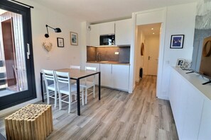 Una cucina moderna con mobili bianchi, un tavolo da pranzo con sedie e uno sgabello di legno.