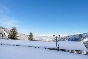 A snow-covered landscape with a clear sky, a wooden fence, and snow-laden trees.
