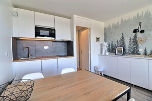 A modern kitchen with white cabinets, a Bosch microwave, and a wooden dining table. - 10m from ski slopes, 2nd floor, balcony, 27m², Méribel-Mottaret (Méribel - Les Allues)