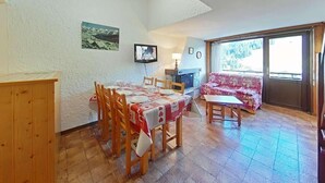 A dining area with a table set for four, wooden chairs, a sofa, and a fireplace.