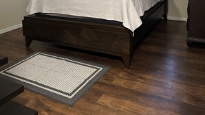 A bedroom with a bed, a ceiling fan, a window with blinds, and a dark wooden floor. - Cozy Family-sized Townhome (Pharr)