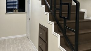A staircase with a geometric railing design, a wall-mounted sign saying "LET'S stay HOME", and a window with blinds. - Cozy Family-sized Townhome (Pharr)