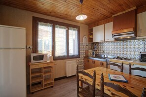 Compact kitchen with gas stove, oven, and wooden dining table.