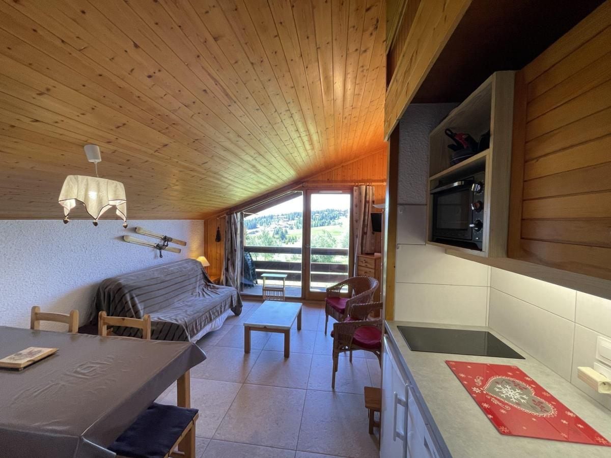 Interior acogedor de una cabaña con comedor, sofá, cocina equipada con microondas y vistas amplias por el gran ventanal.