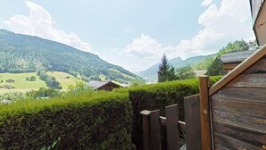 En træterrasse med udsigt over et grønt landskab og fjerne bjerge.
