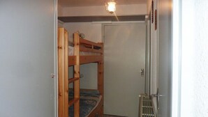 Een kleine, afgesloten kamer met een stapelbed, een deur en een radiator.