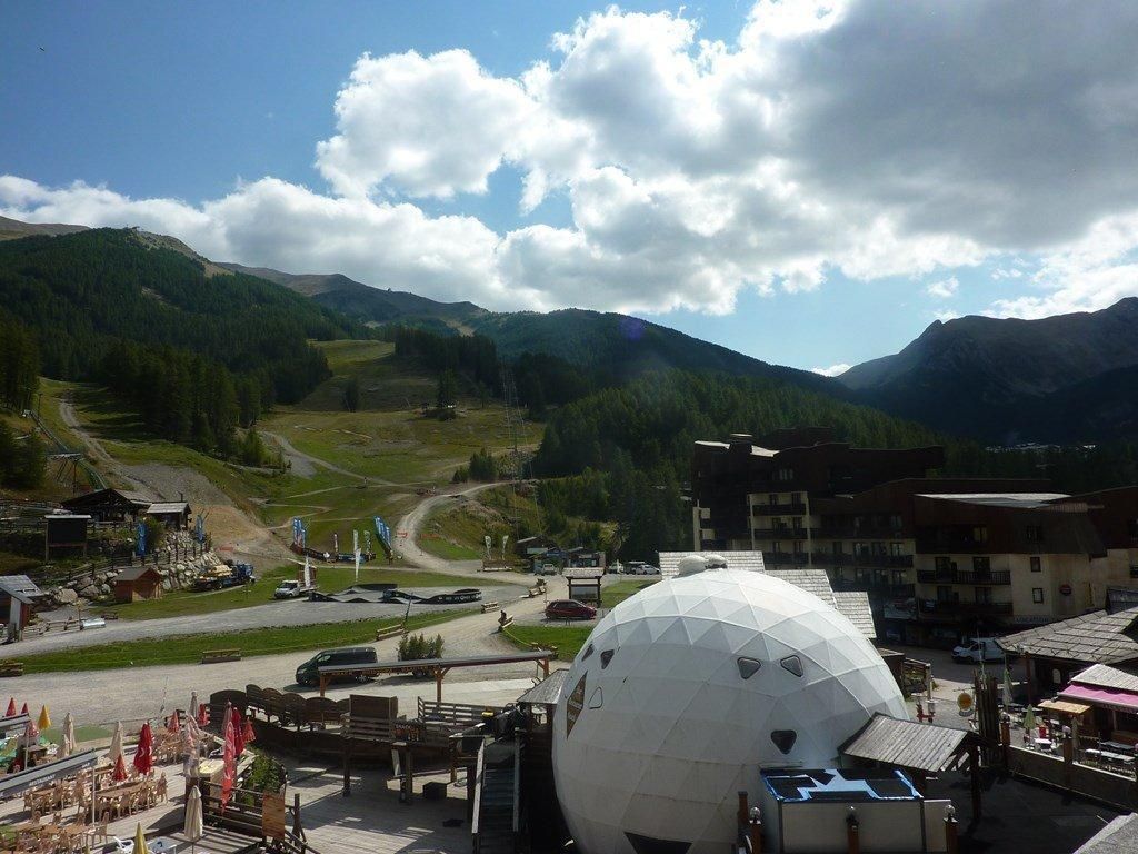 A mountainous landscape with a large spherical structure, possibly a geodesic dome, in the foreground.