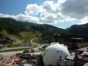 A mountainous landscape with a large spherical structure, possibly a geodesic dome, in the foreground.