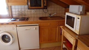 A compact kitchen with a washing machine, a microwave, and a toaster. - 4th floor, balcony, parking, tv, ski locker, 55m², Saint Gervais (Saint-Gervais-les-Bains)