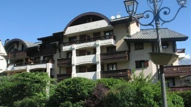 A multi-story building with balconies, a street lamp, and lush greenery in front. - 4th floor, balcony, parking, tv, ski locker, 55m², Saint Gervais (Saint-Gervais-les-Bains)