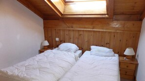 A room with two beds, wooden walls, a skylight, and bedside lamps. - 4th floor, balcony, parking, tv, ski locker, 55m², Saint Gervais (Saint-Gervais-les-Bains)