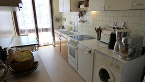 Une cuisine équipée d’un lave-linge, d’une cuisinière et d’un évier.