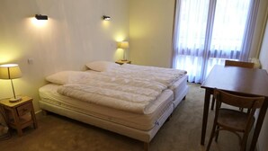 Une chambre à coucher avec un lit double, des lampes de chevet, une petite table et une chaise.