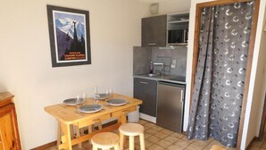 Une cuisine compacte comprenant une table à manger pour quatre personnes, un réfrigérateur et un four à micro-ondes.