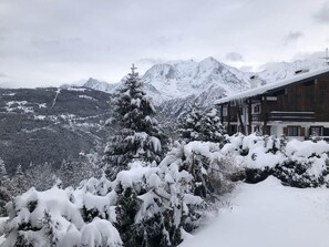 Een besneeuwd berglandschap met een houten gebouw.
