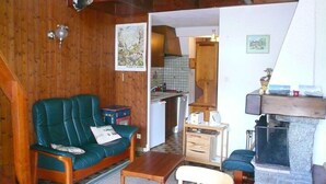 Un salon chaleureux avec un canapé vert, une petite table et une cheminée.