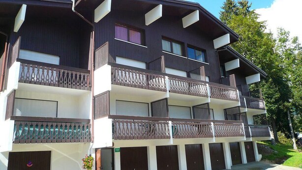 Un immeuble à plusieurs étages doté de balcons et d’une entr ée de garage.