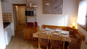 A compact kitchen with a washing machine, a microwave, and a dining area with a table set for two. - 200m from ski slopes, 3rd floor, view mountain, balcony, parking, tv, ski locker, 38m² (Les Contamines-Montjoie)
