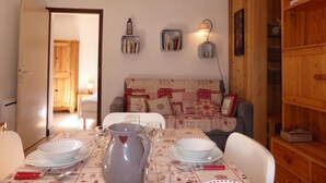 Un comedor acogedor con una mesa dispuesta para dos, una estantería y un sofá al fondo.