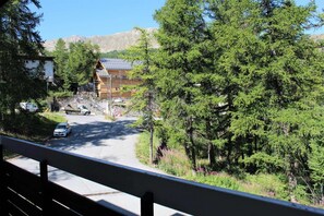 Una baita con rivestimento in legno, un vialetto e montagne sullo sfondo.