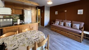 A compact living space with a kitchenette, dining table, and a sofa with decorative pillows. - 10m from ski slopes, 2nd floor, terrace, tv, 28m², Sauze - Super Sauze (Enchastrayes)