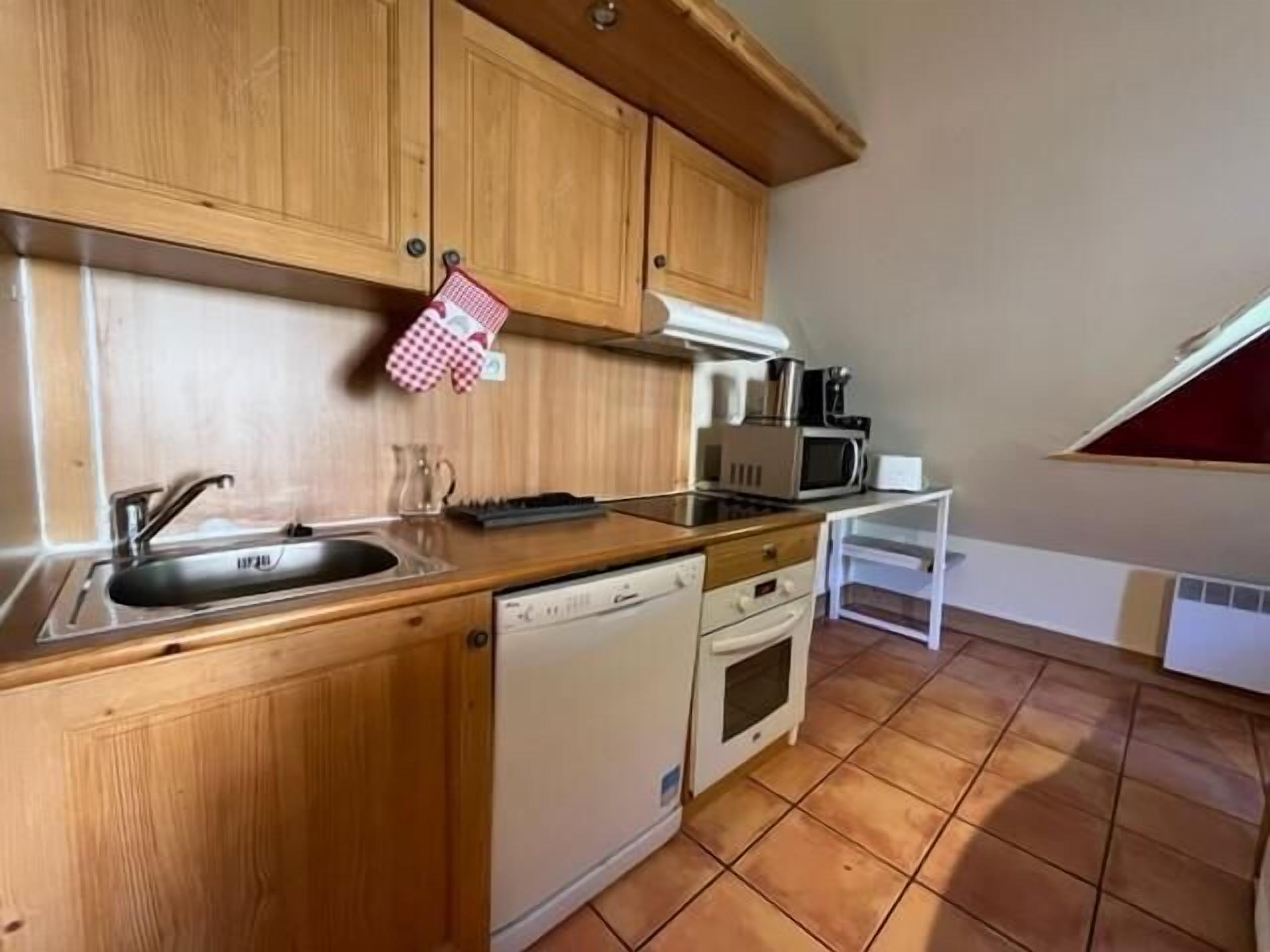 Una cucina compatta con mobili in legno, lavastoviglie, forno a microonde e macchina del caffè.