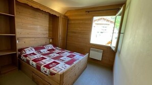 Una stanza accogliente e piccola con un letto di legno, una finestra e un termosifone.