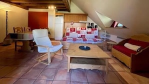 Un soggiorno accogliente con soffitto in legno, un tavolo da pranzo, un divano e un angolo cottura con pensili e frigorifero.