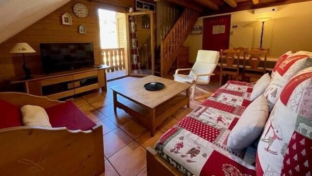 Un accogliente soggiorno con soffitto in legno, televisore, divano e tavolo da pranzo.