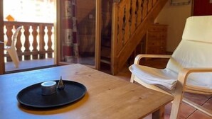 Un tavolo di legno con un piatto e una candela, una sedia bianca e una scala in legno.