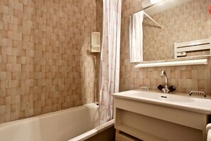 A bathroom with a bathtub, a sink with a mirror, and a shower curtain. - 4th floor, balcony, tv, ski locker, 21m², Chamrousse (Chamrousse)
