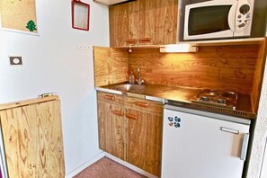 A compact kitchen with wooden cabinets, a microwave, and a small refrigerator. - 4th floor, balcony, tv, ski locker, 21m², Chamrousse (Chamrousse)