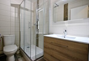 A modern bathroom with a glass shower enclosure, a white toilet, and a wooden vanity with a sink. - 150m from ski slopes, 5th floor, balcony, tv, 30m², Chamrousse (Chamrousse)